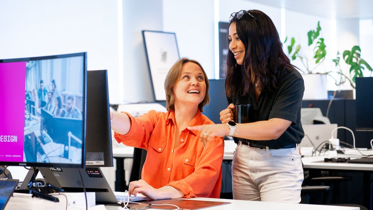 2 colleagues behind laptop laughing